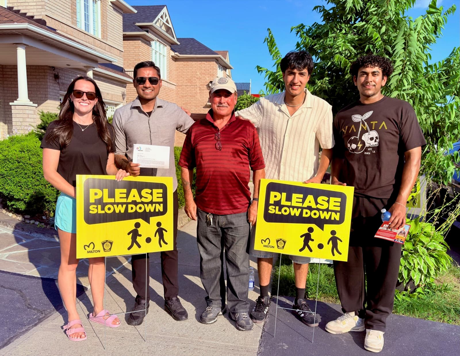 Adil Khalqi handing out 'Please Slow Down' road safety signs in Ward 3